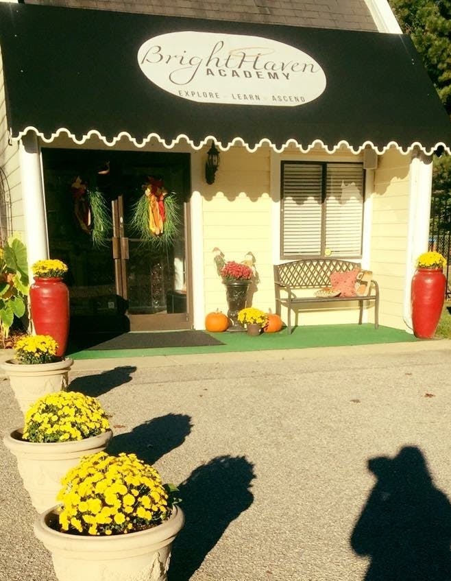 Building with a black awning displaying "Bright Haven Academy" and potted yellow flowers