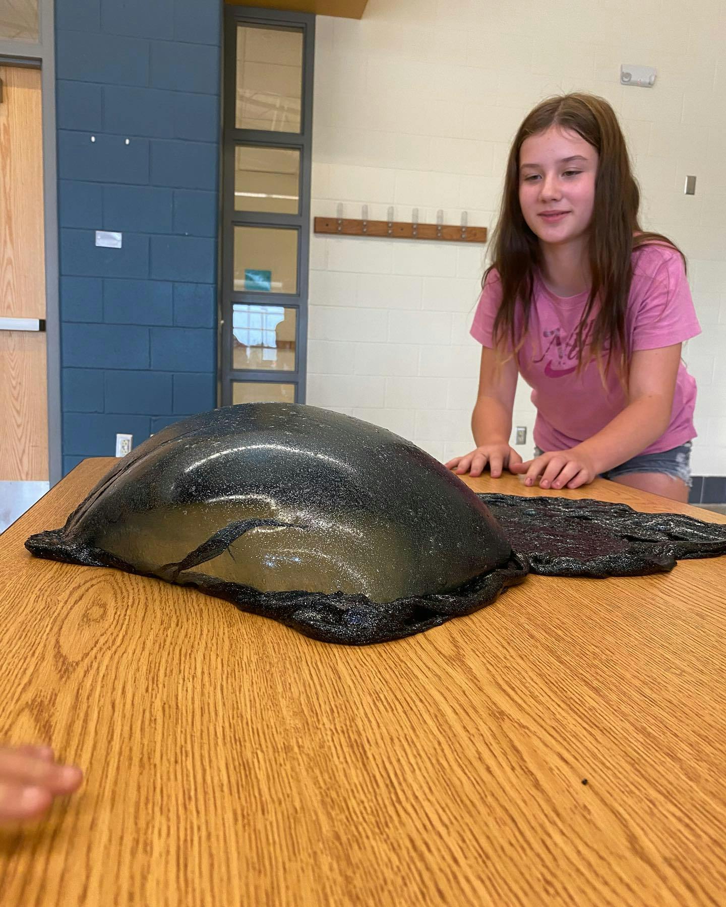 Teen looking at a large blob of dark slime on a wooden table