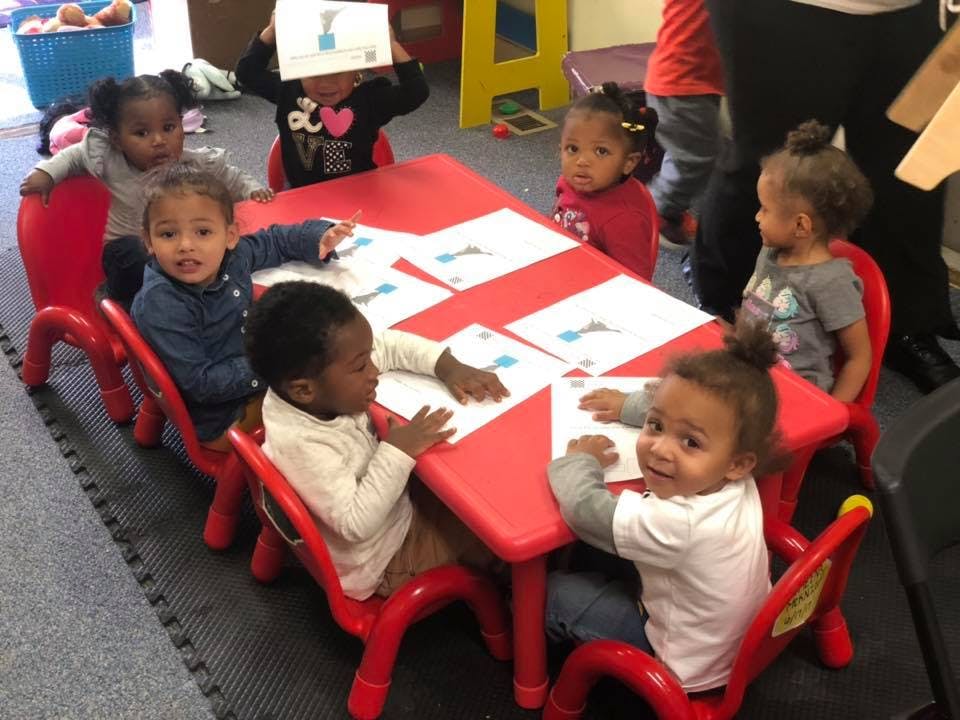 Children sitting at a red table with papers
