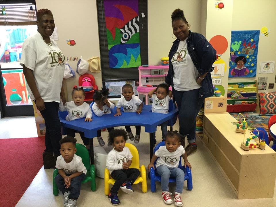 Two adults with several children in a classroom