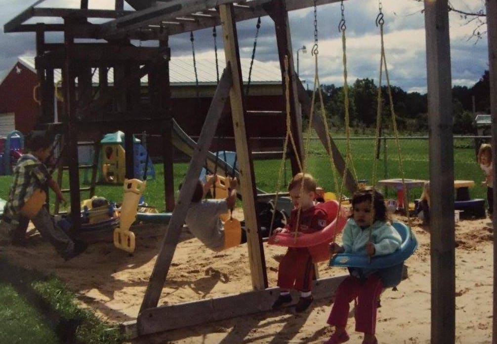 Children on swings and playing in a sandbox on a playground