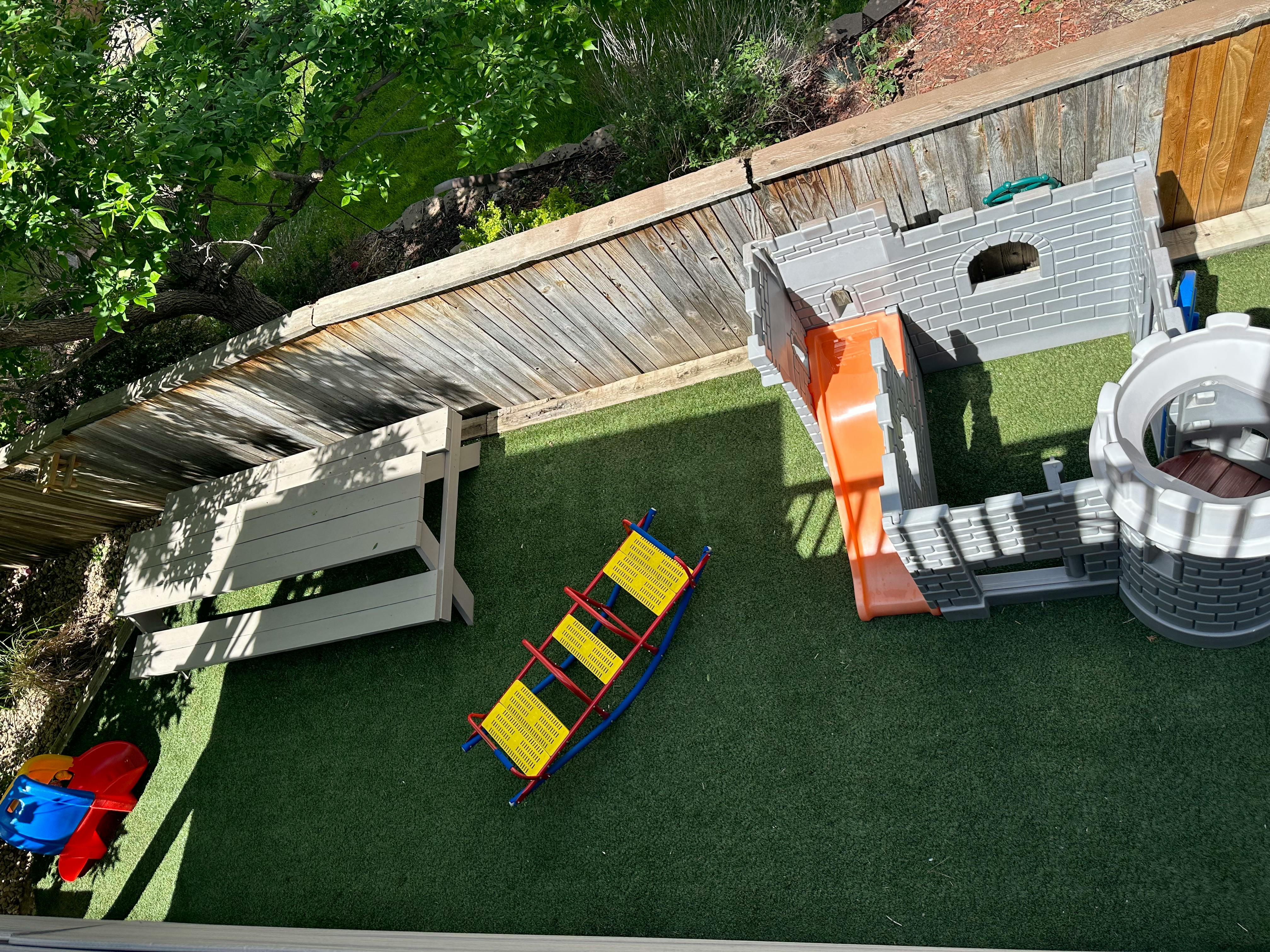 Playground with a slide, climbing structure, and seesaw on artificial turf