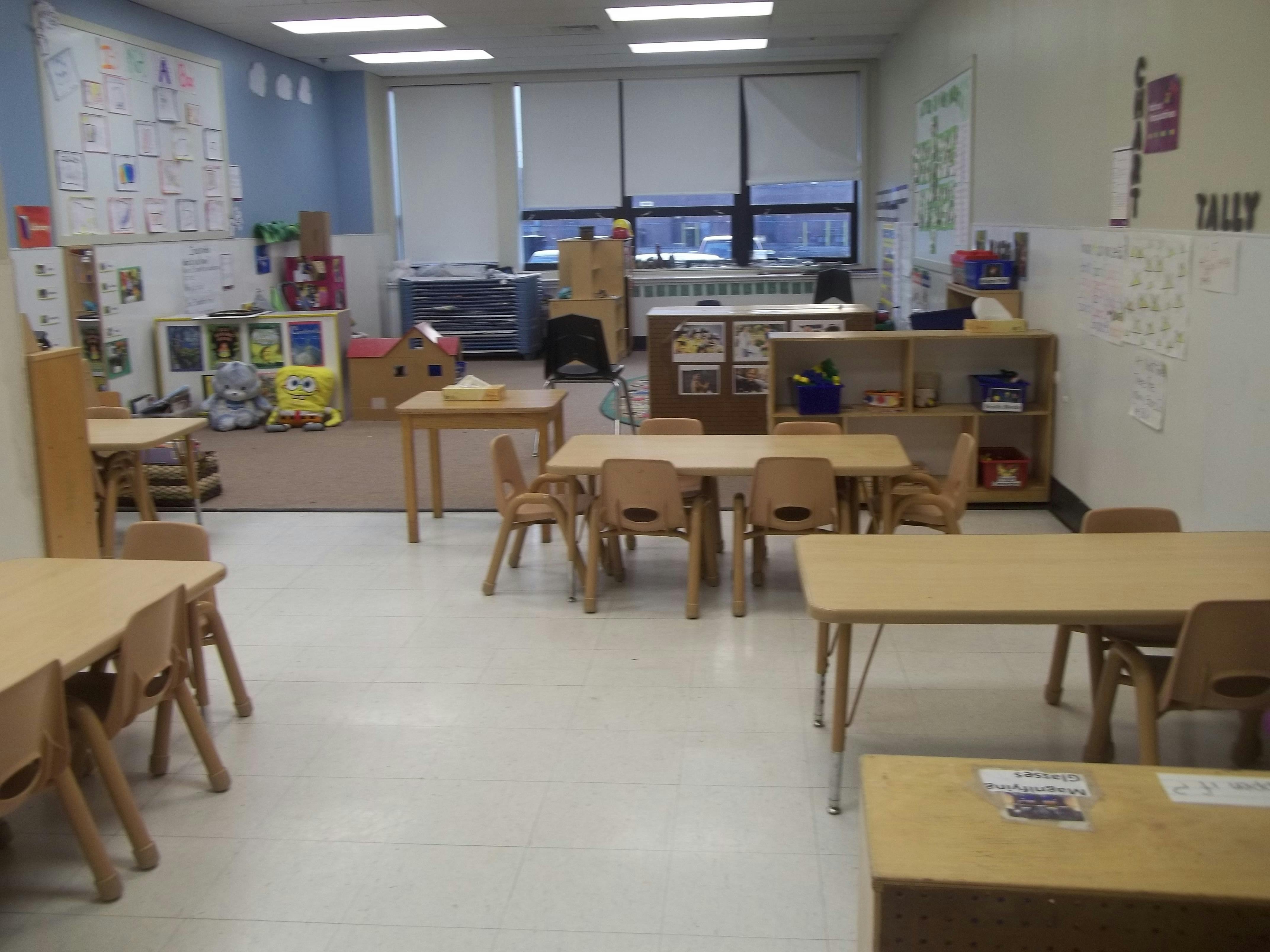 Empty classroom with small tables and chairs, whiteboards with drawings