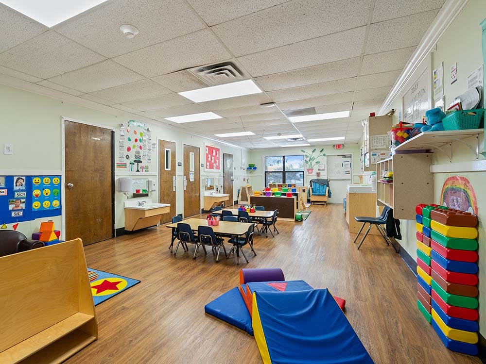 Empty children's classroom with small tables and play equipment
