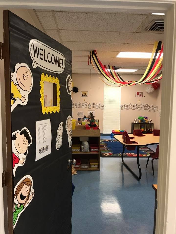 Open classroom door with "WELCOME" sign and cartoon character cutouts