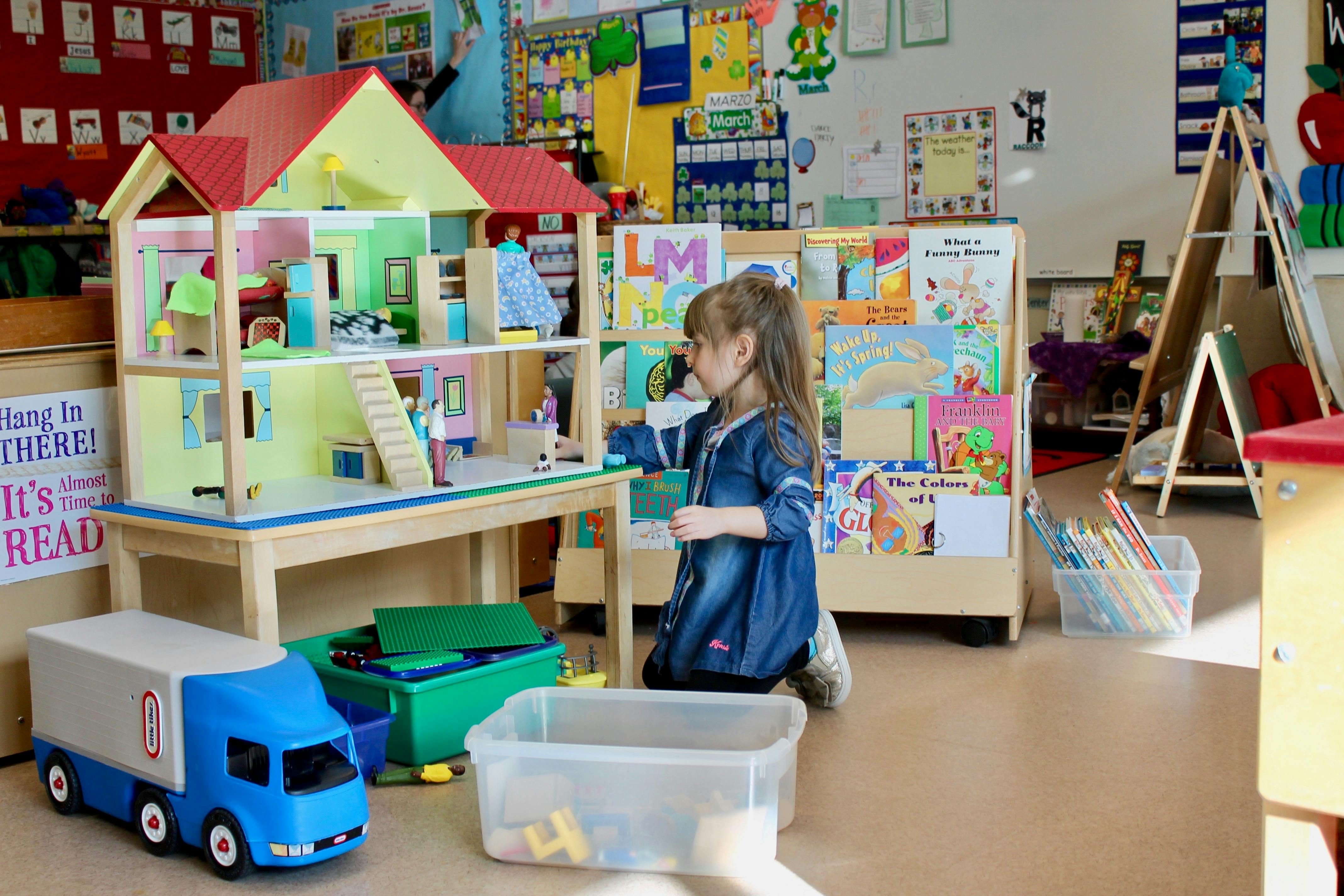 Child playing with a dollhouse in a classroom