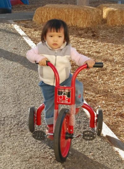 Child riding a red tricycle outdoors