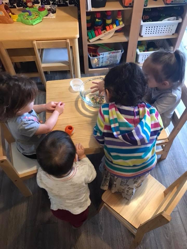 Four children gathered around a small table with a bowl