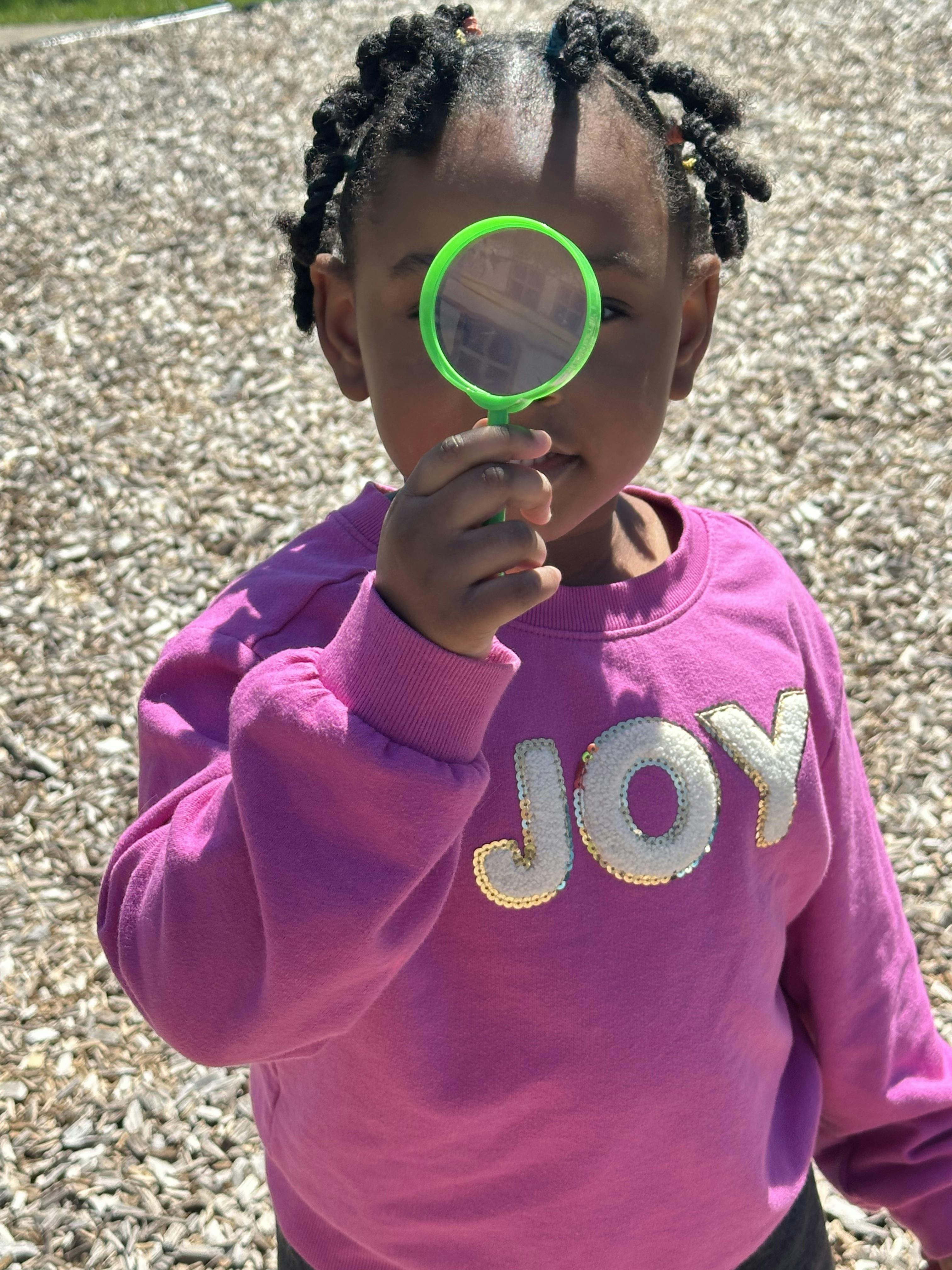 Child looking through a green magnifying glass