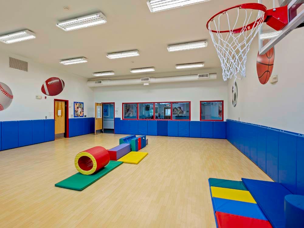 Indoor play area with colorful soft play equipment and a basketball hoop