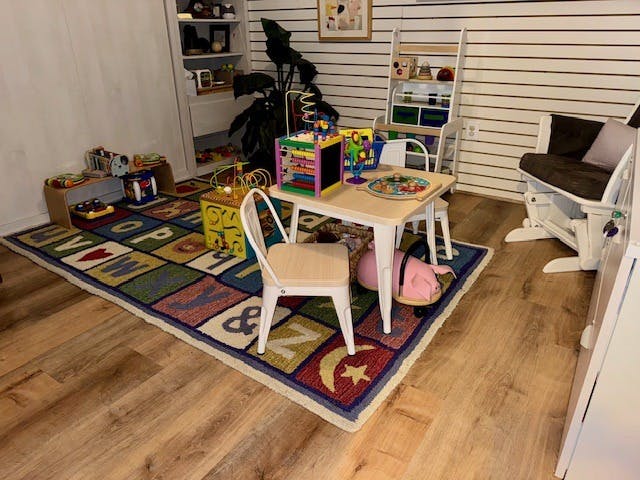 Playroom with children's table, chairs, and educational toys on an alphabet rug