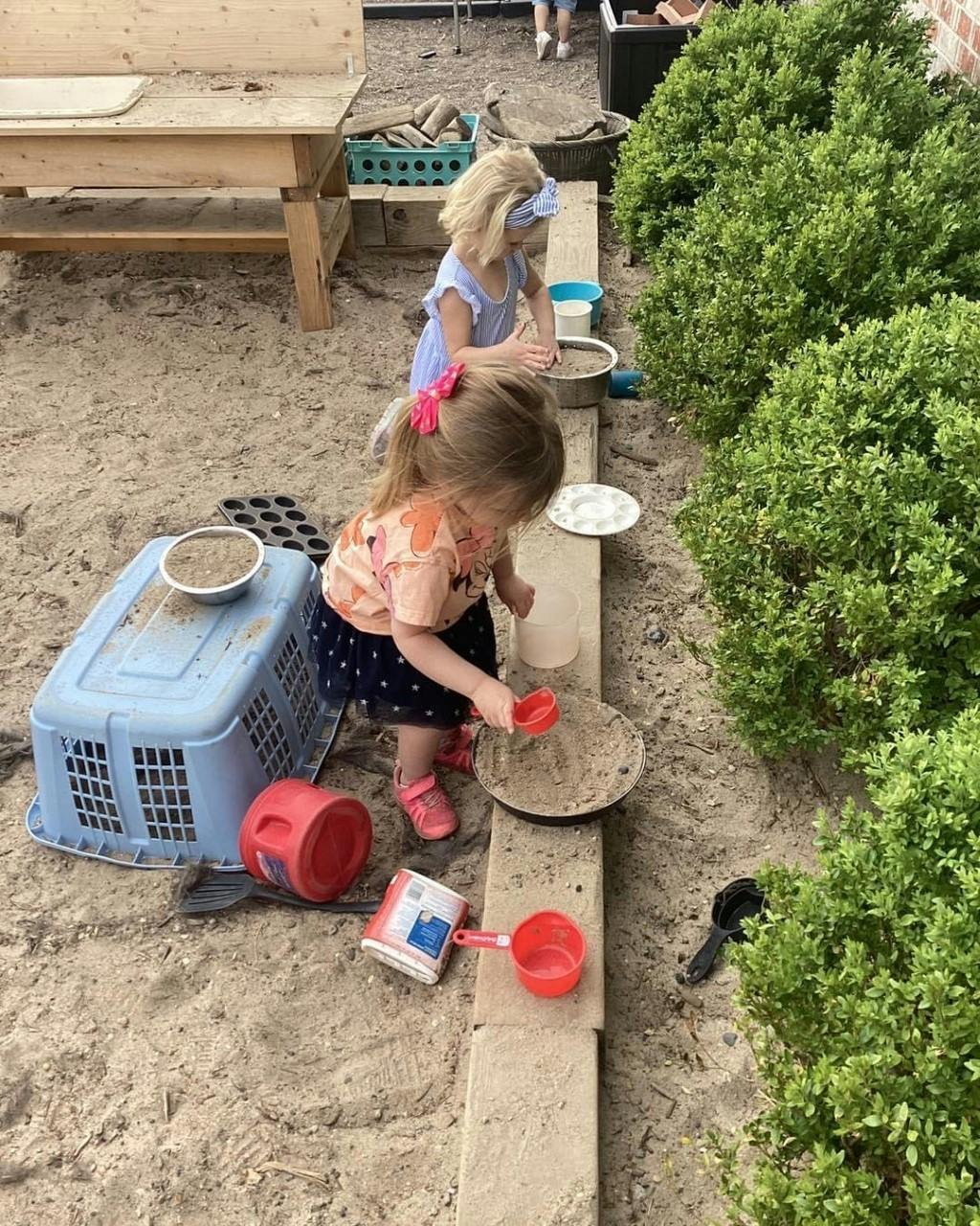 Two children playing in a sandbox with toys