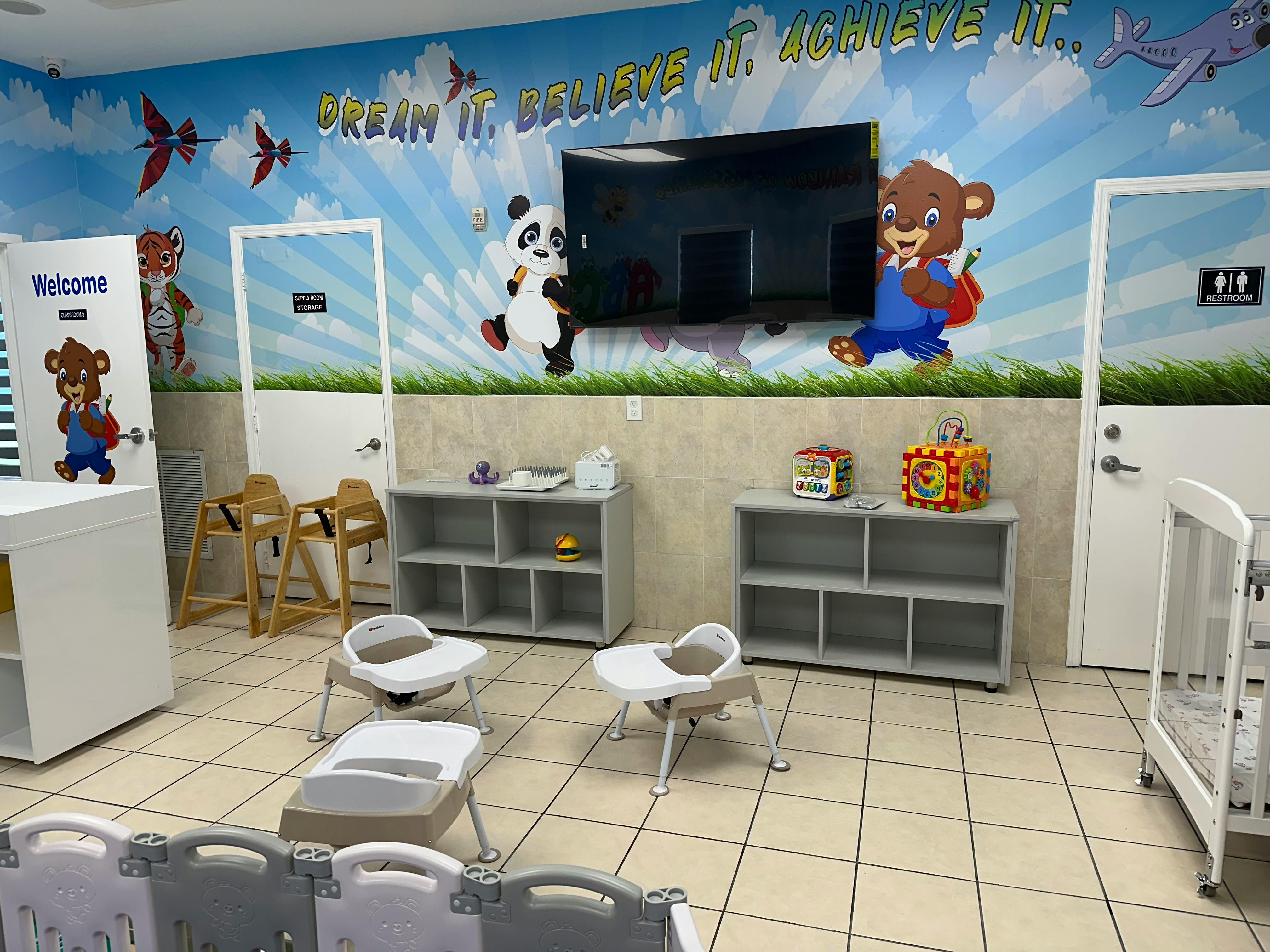 Childcare room with colorful wall mural, high chairs, and shelves