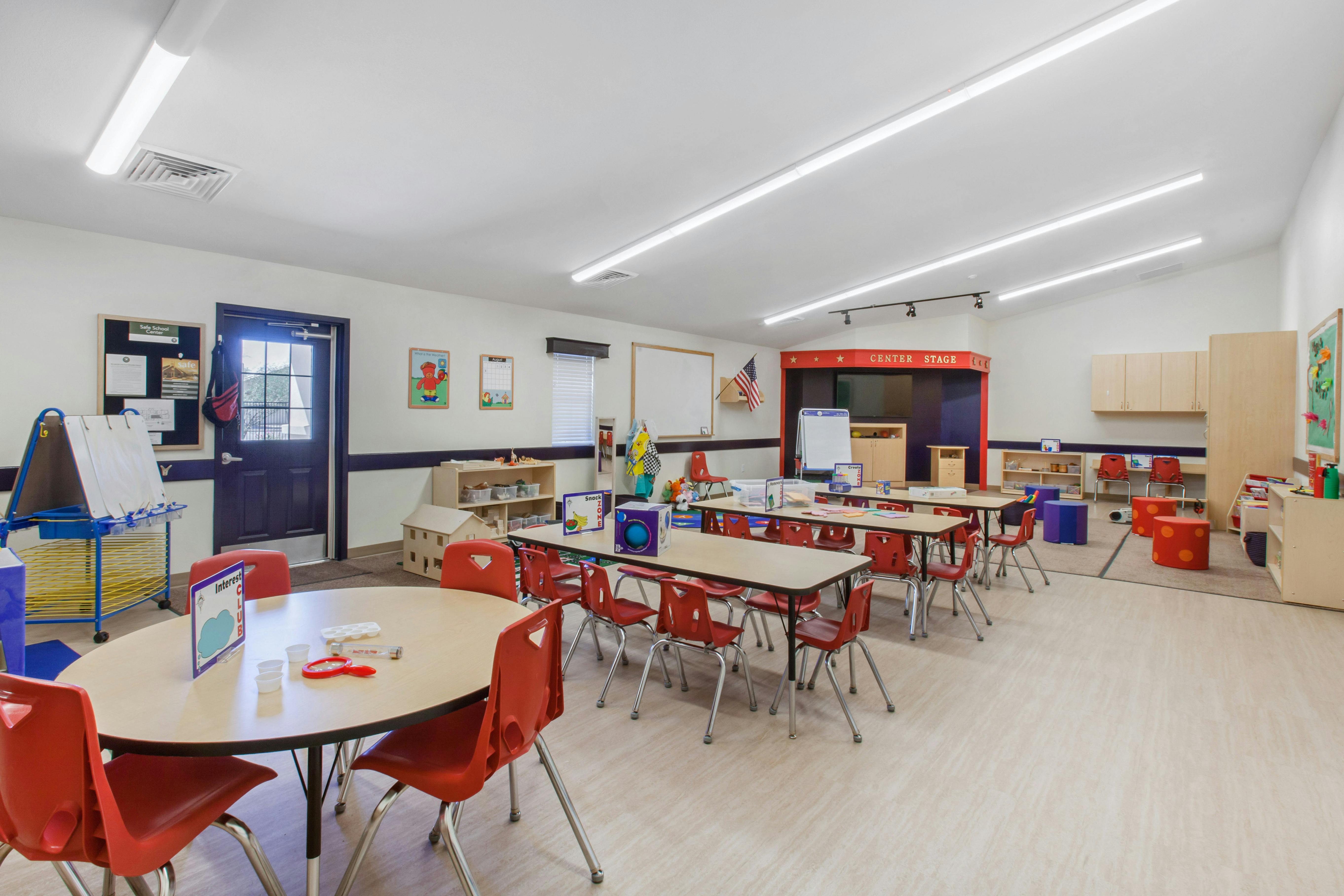 Classroom with child-sized tables and chairs, a stage area labeled "Center Stage"
