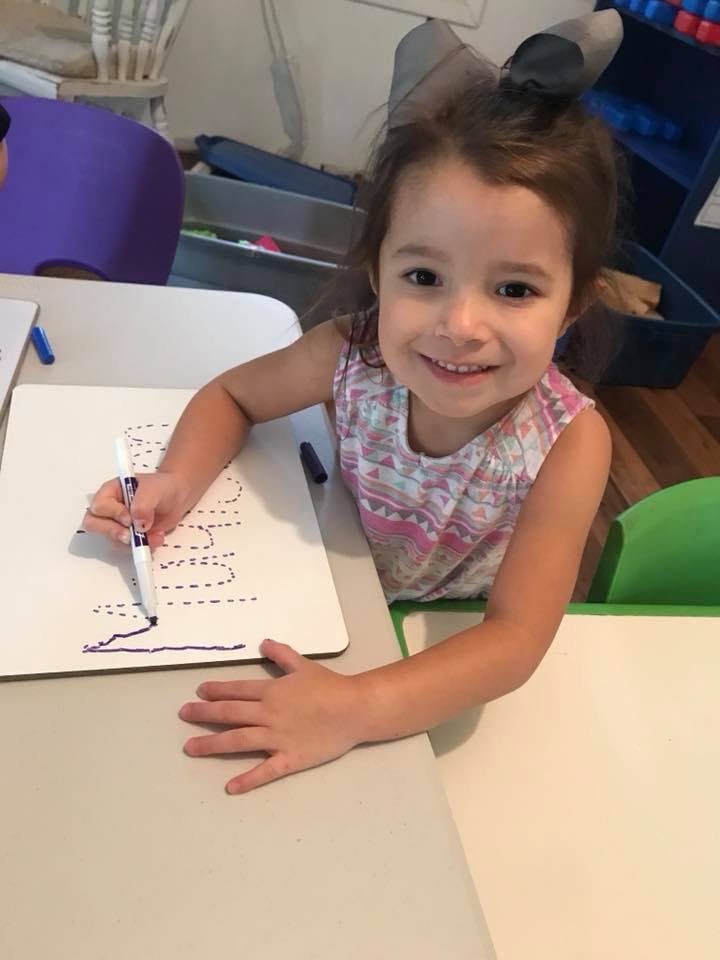 Child writing on a whiteboard at a table