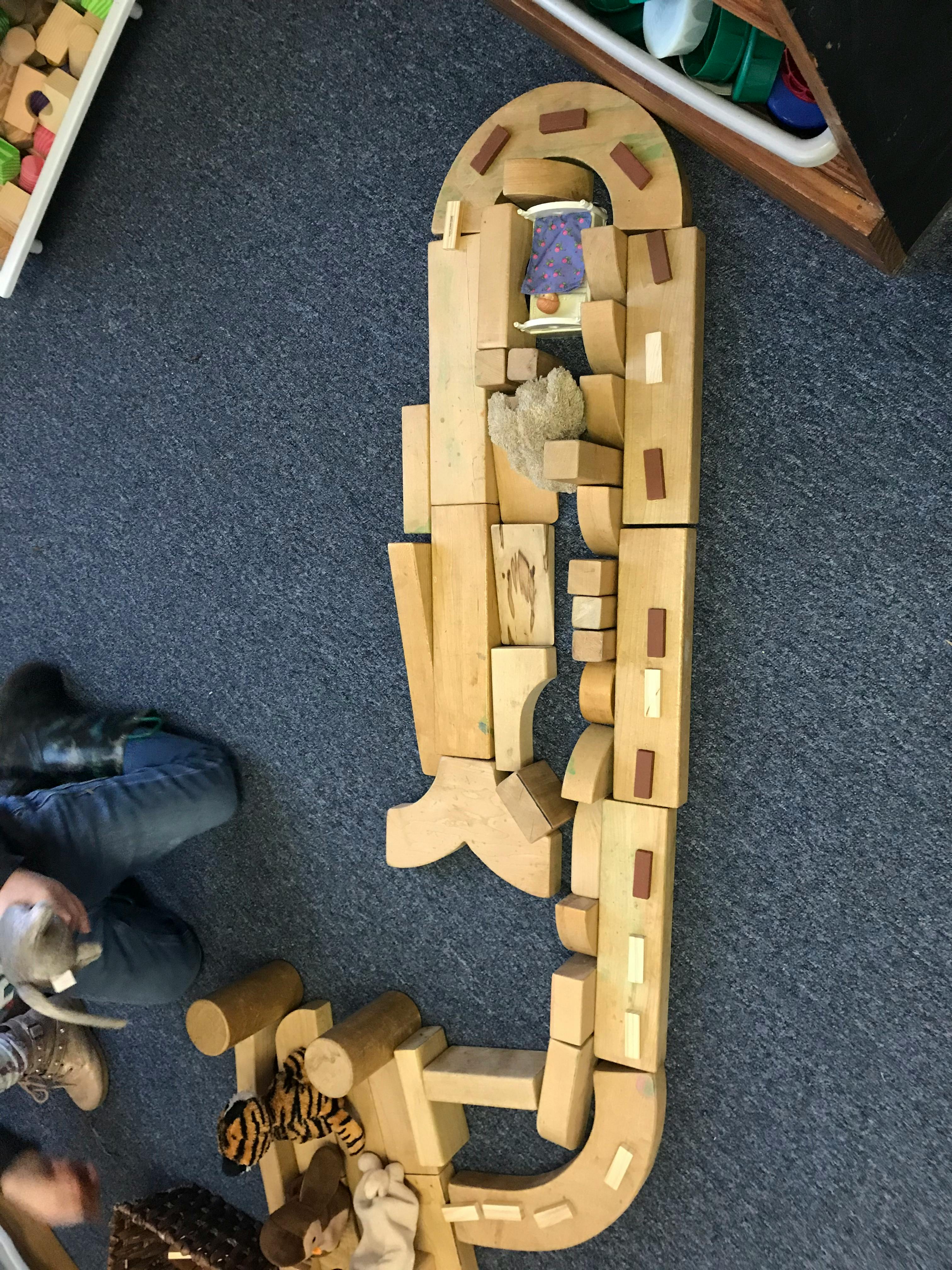 Wooden blocks arranged to form a road with a person sitting nearby