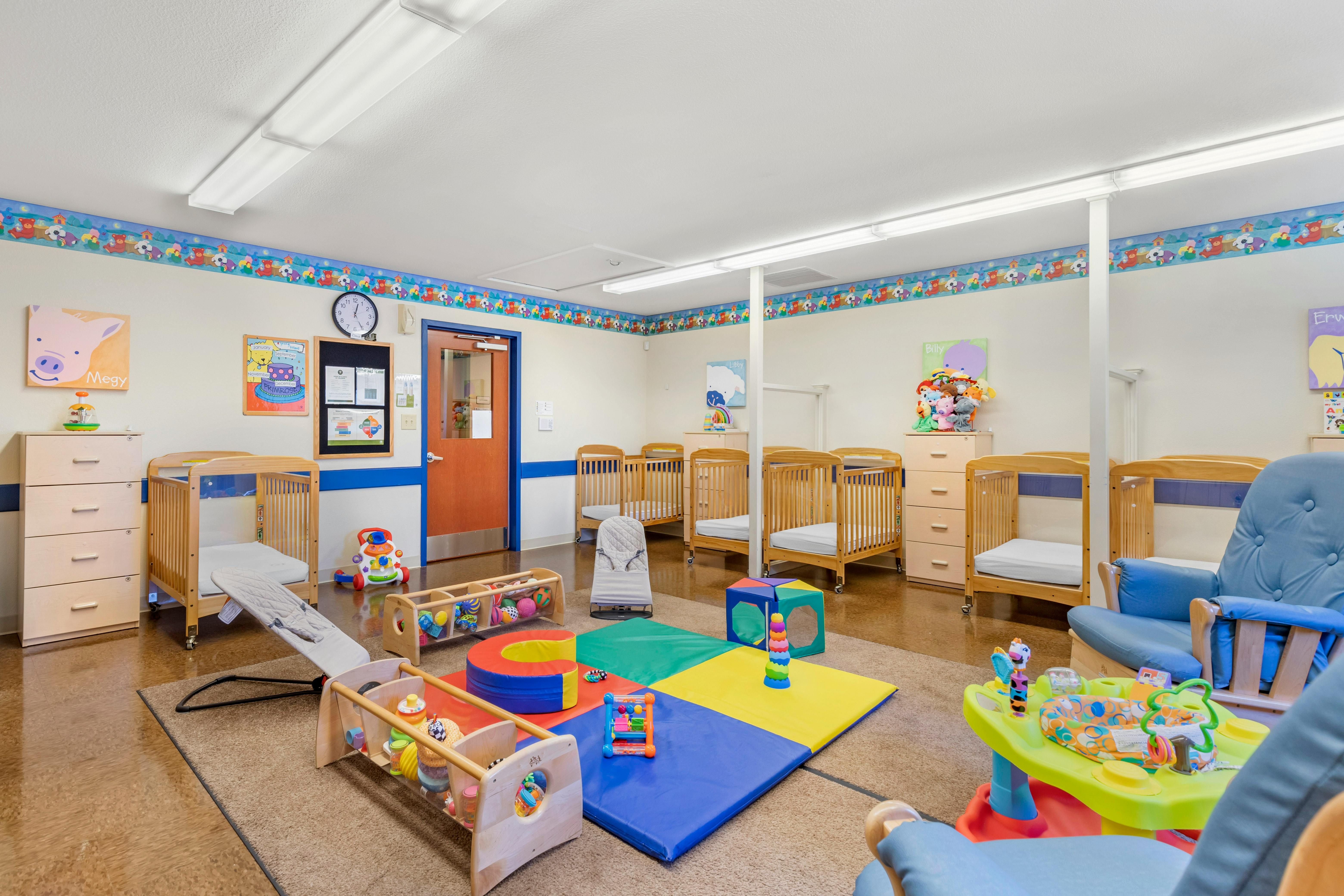A colorful room with cribs, playmats, and toys for infants or toddlers