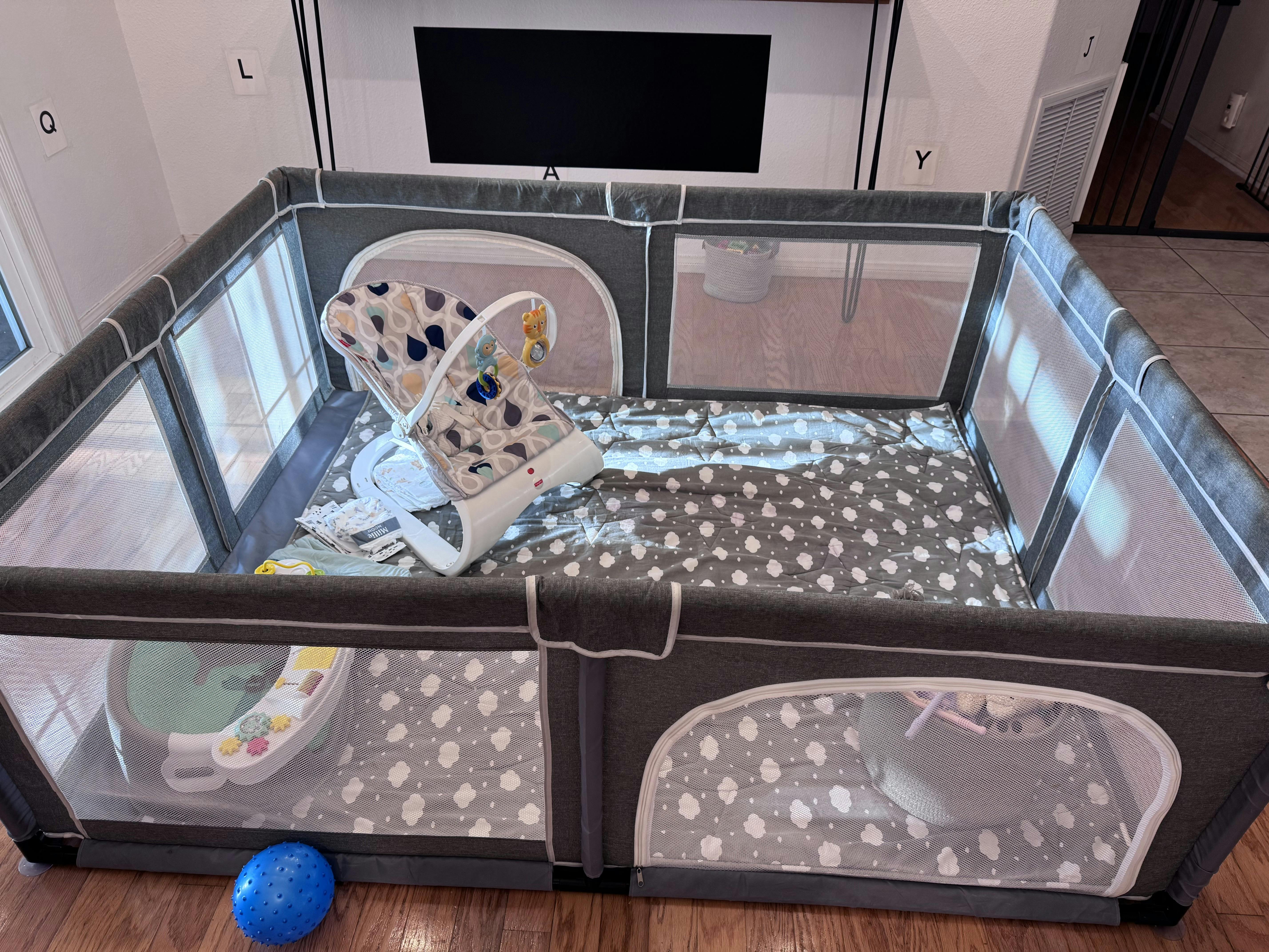 Empty baby playpen with a bouncer and other toys inside