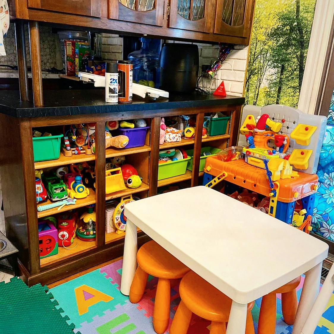 Playroom with toy shelves, a child's table and stools, and a toy workbench
