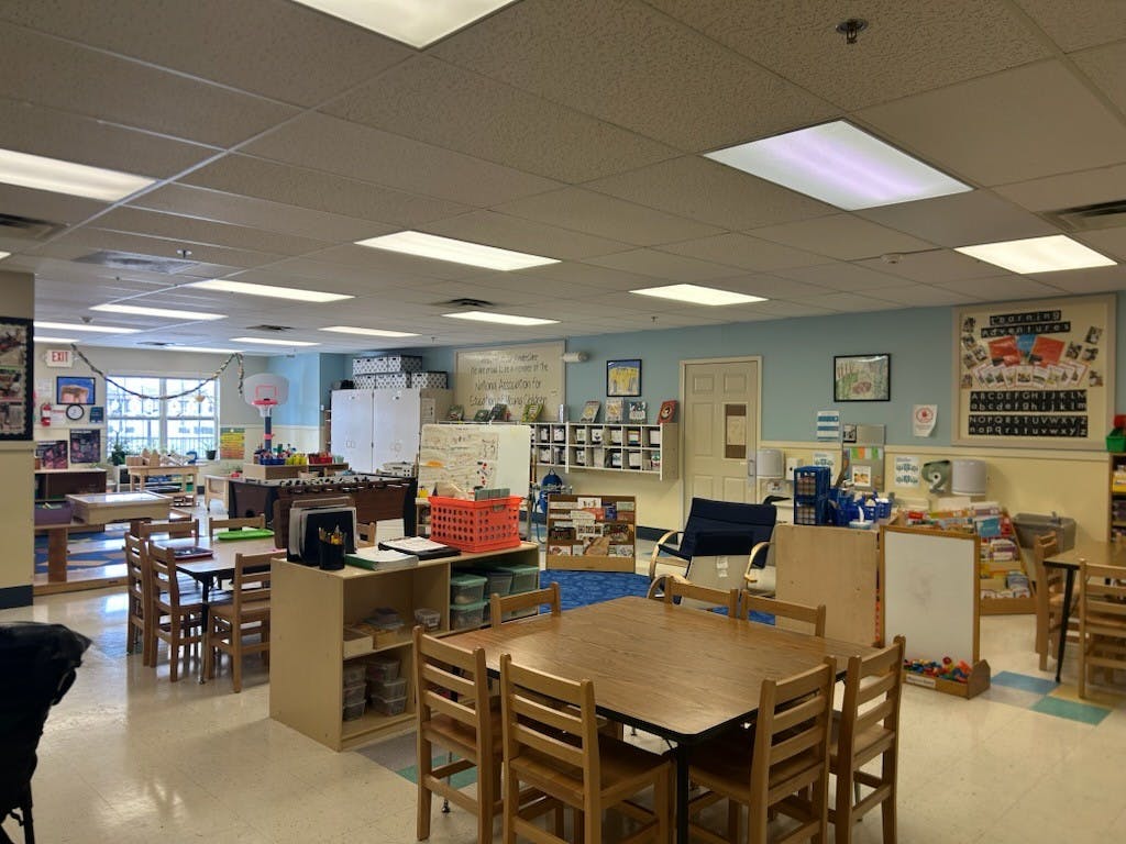 Classroom with tables, chairs, bookshelves, and a small basketball hoop
