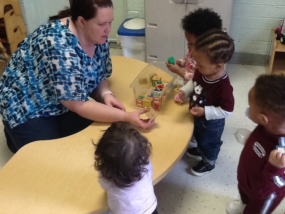 Person and three children playing with blocks at a table