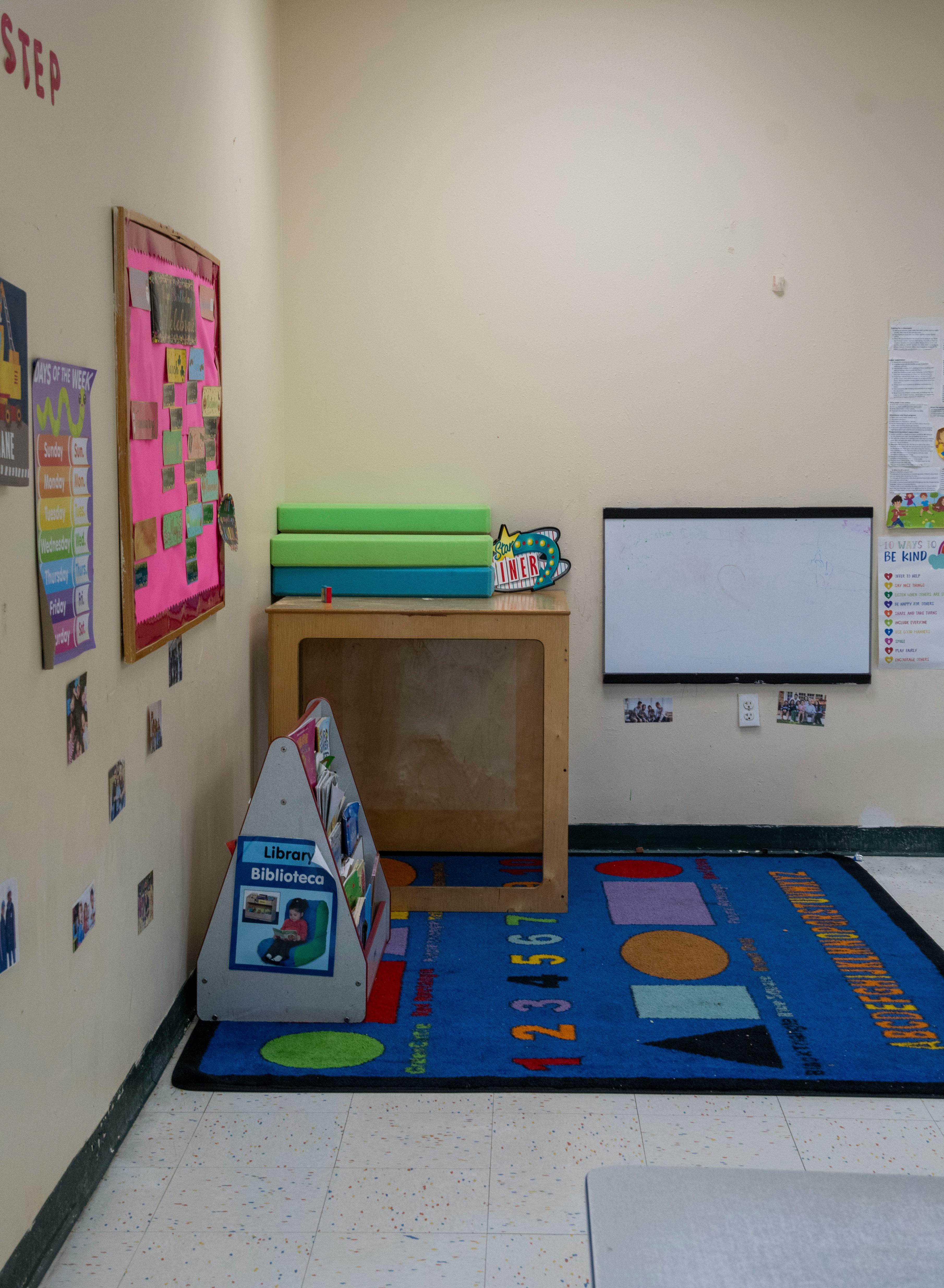 Classroom corner with a blue rug, book display, and whiteboard