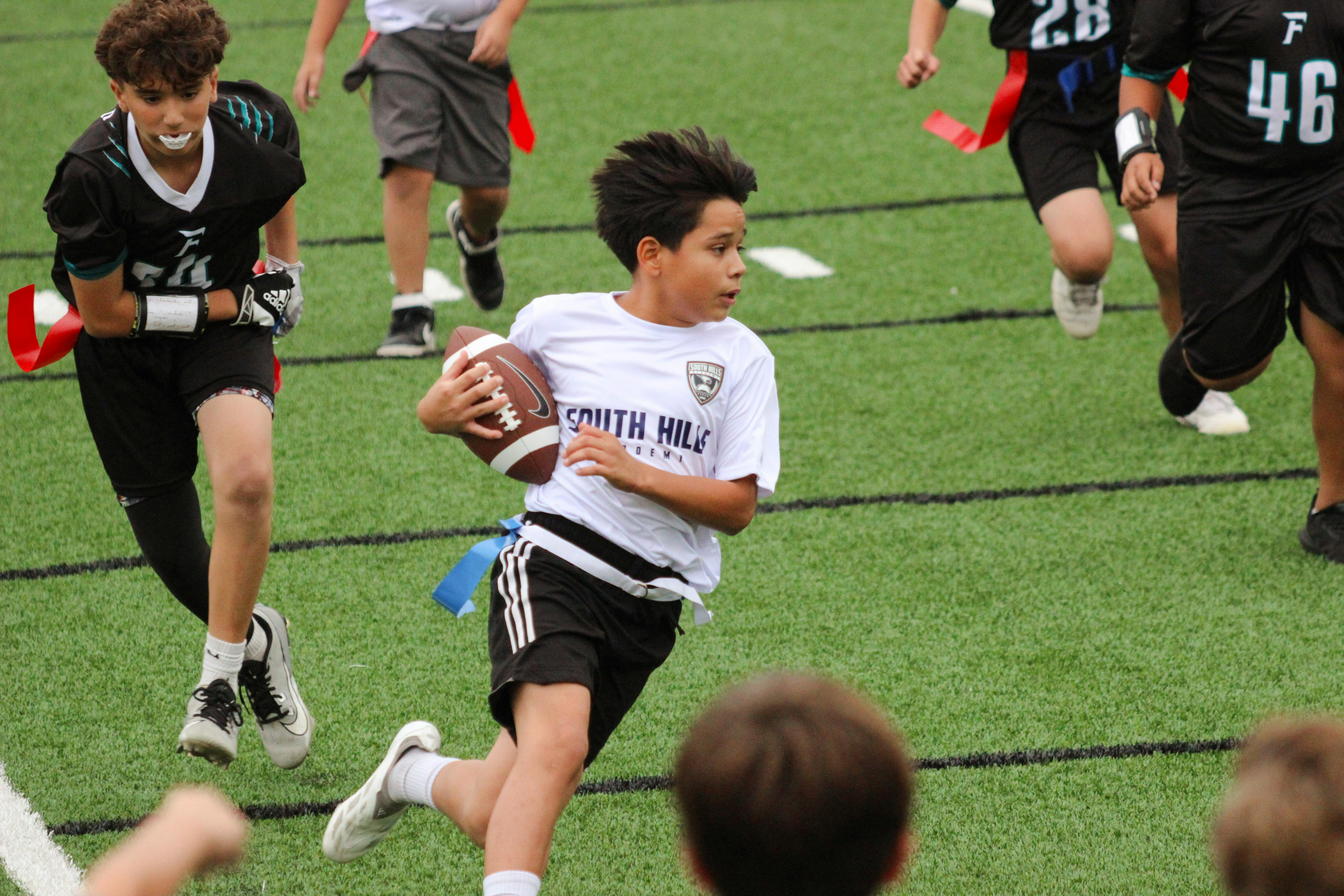 Child running with a football during a flag football game