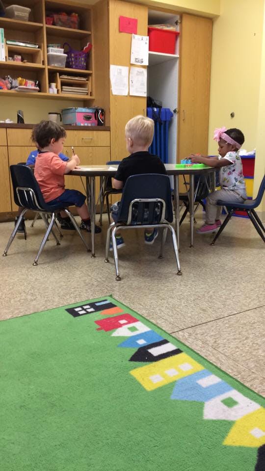 Three children sitting at a table in a classroom