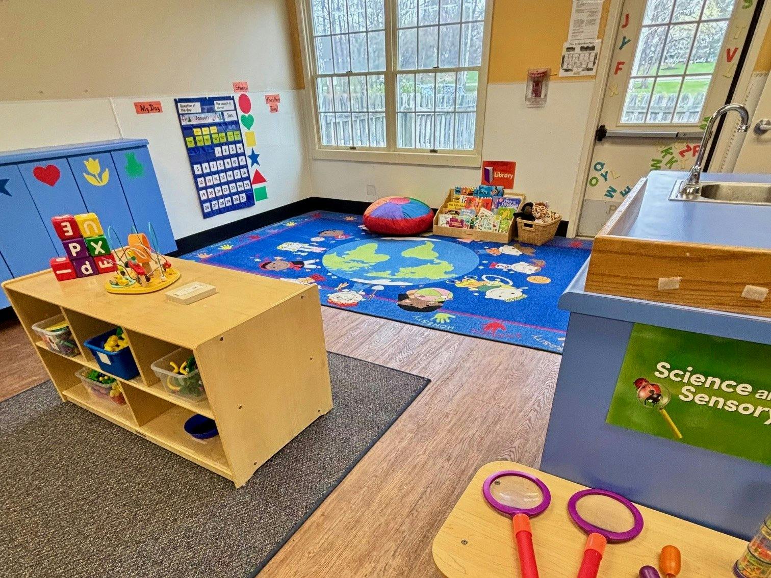 Classroom with a colorful rug, toys, and activity centers
