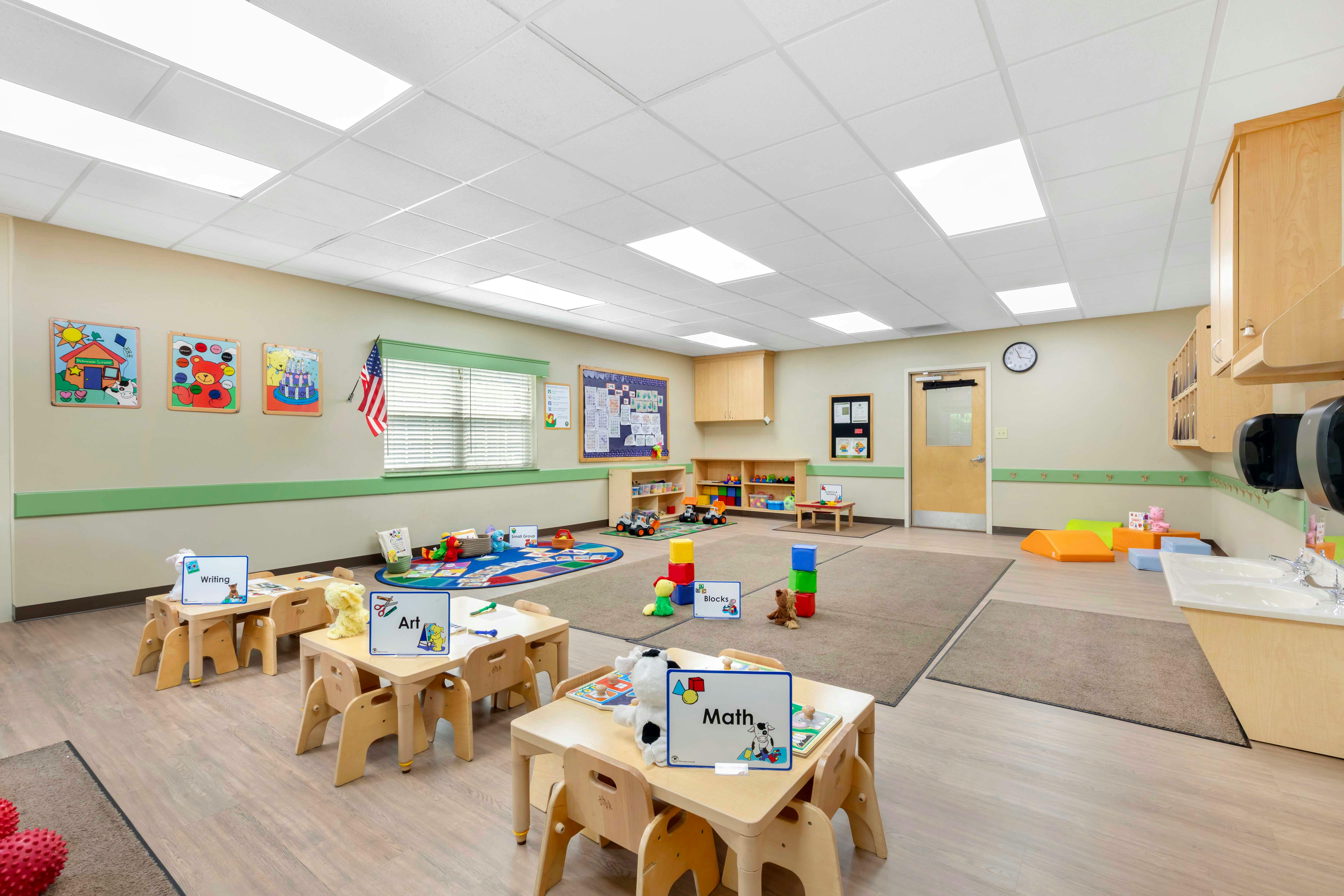 Classroom with small tables, chairs, and play areas
