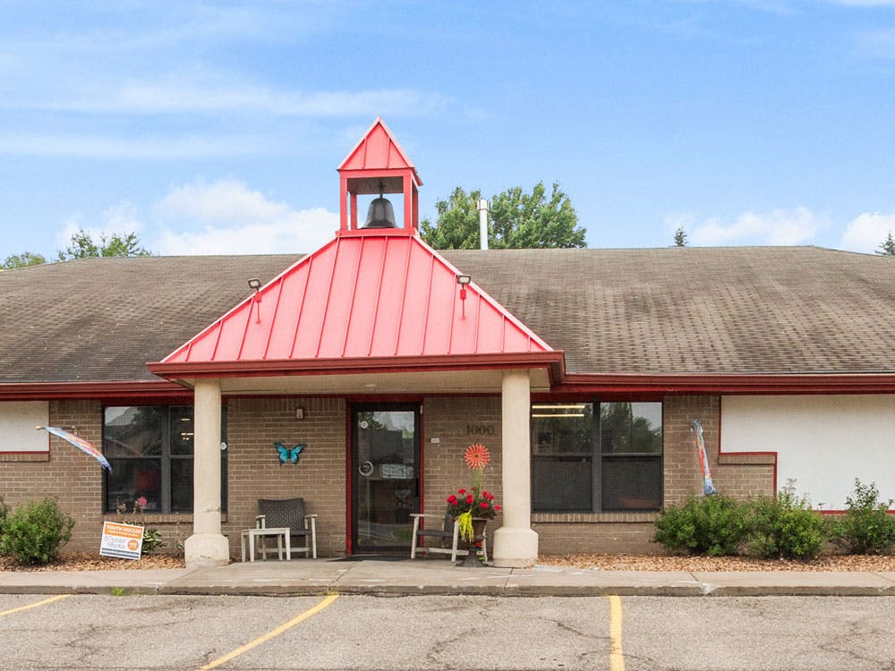 Front exterior of a brick building with a red roof and bell tower