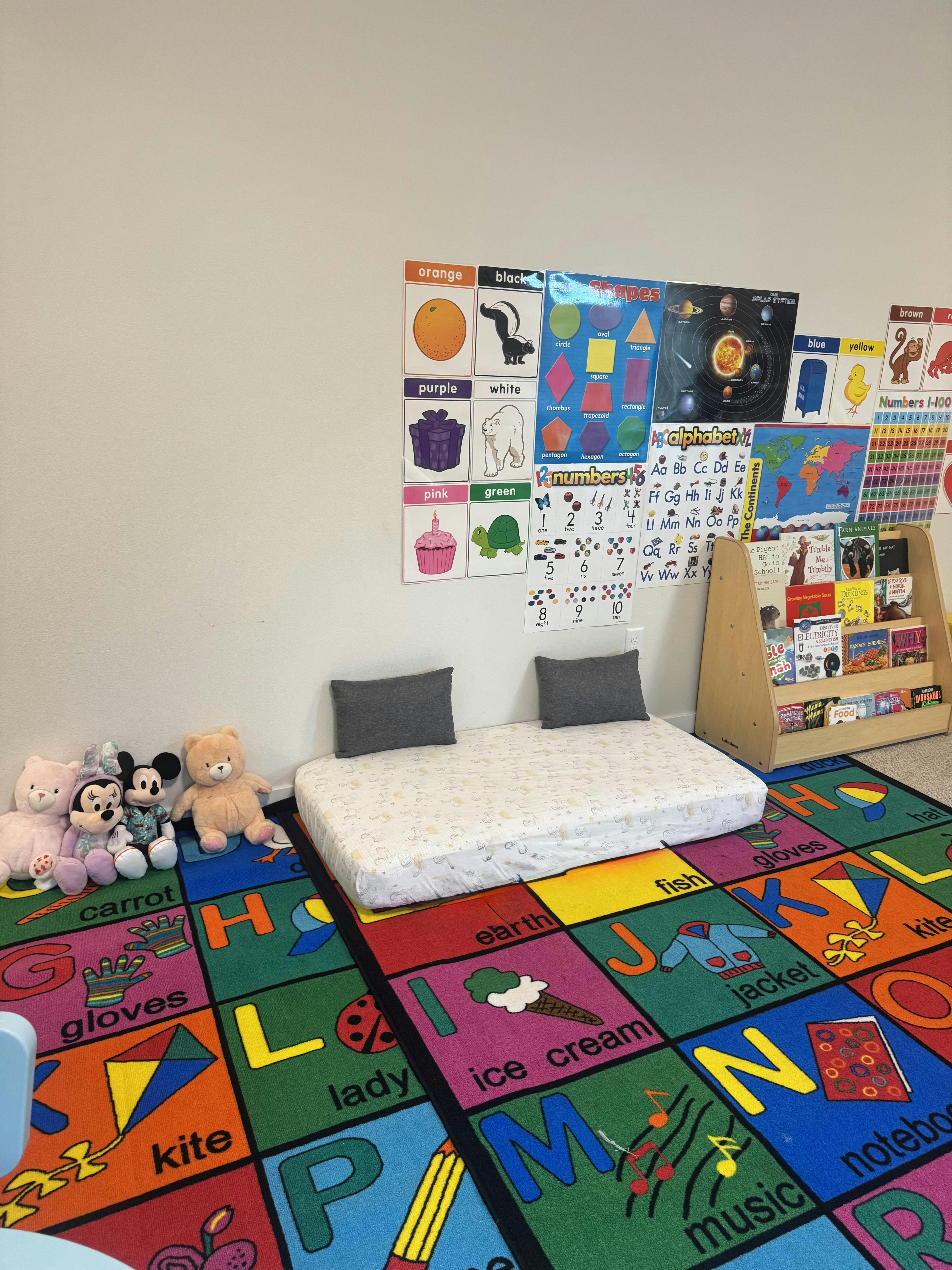 A low floor bed with educational posters and a bookshelf in a classroom