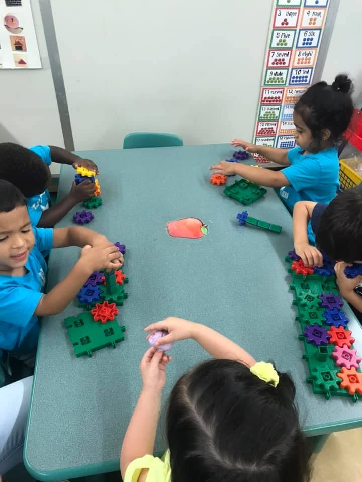 Children playing with colorful interlocking gears at a table