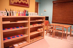 Shelves with learning materials and small tables in a classroom