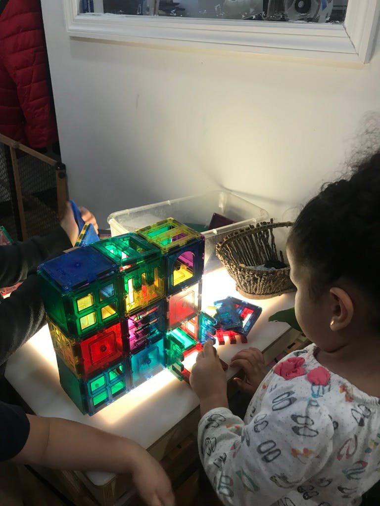 Child playing with colorful magnetic blocks on a light table