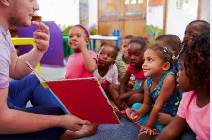 Person reading a book to a group of children