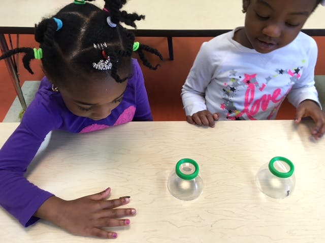 Two children looking down at objects on a table