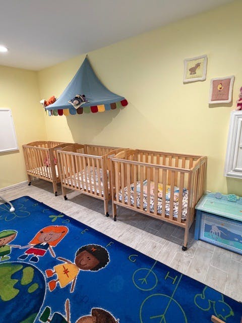 Three wooden cribs with mattresses next to a blue rug with alphabet rug