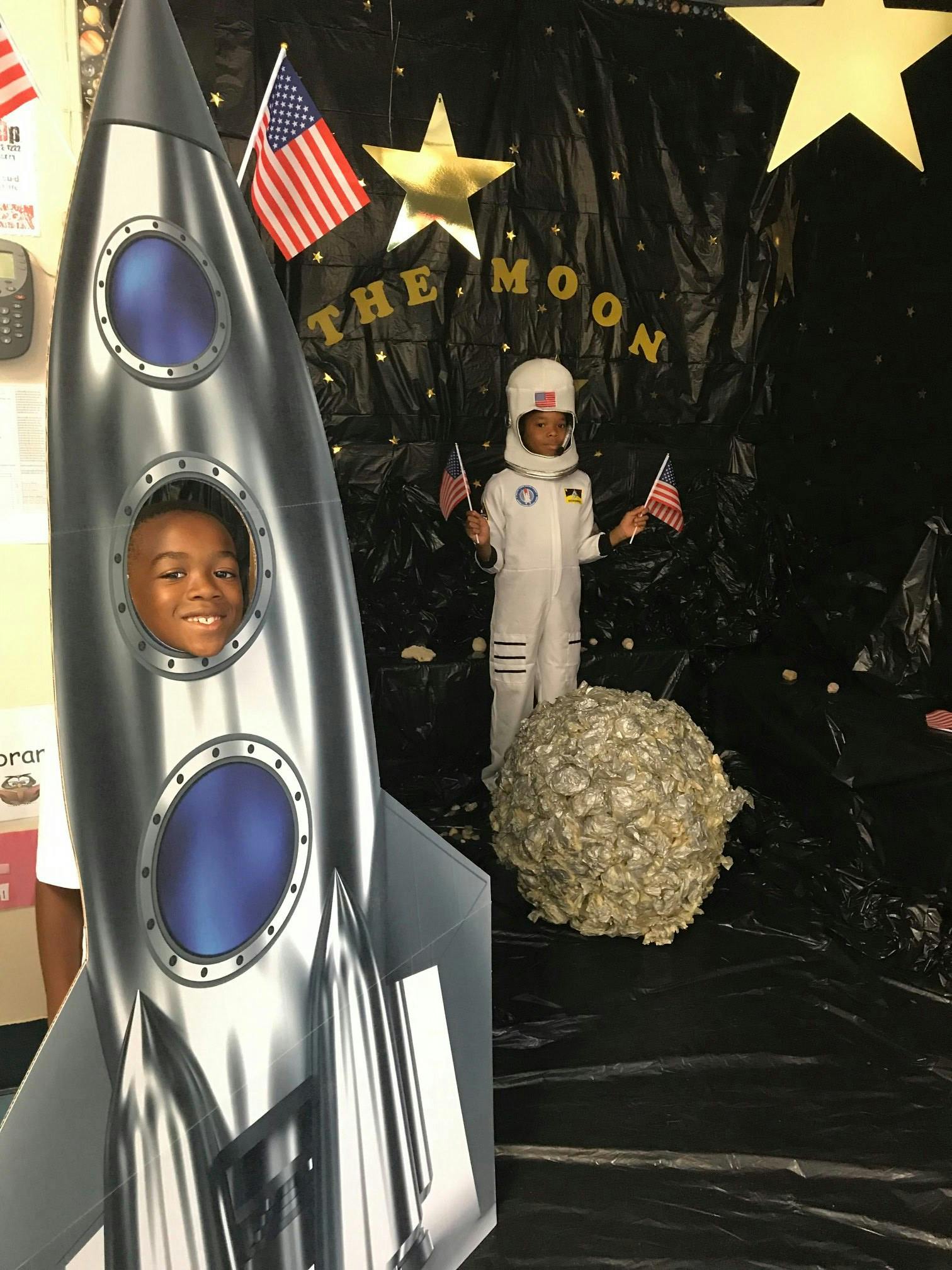 Child in a rocket cutout and a child in an astronaut costume holding flags