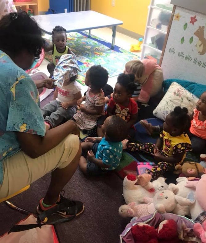 Adult and multiple children sitting on the floor in a classroom