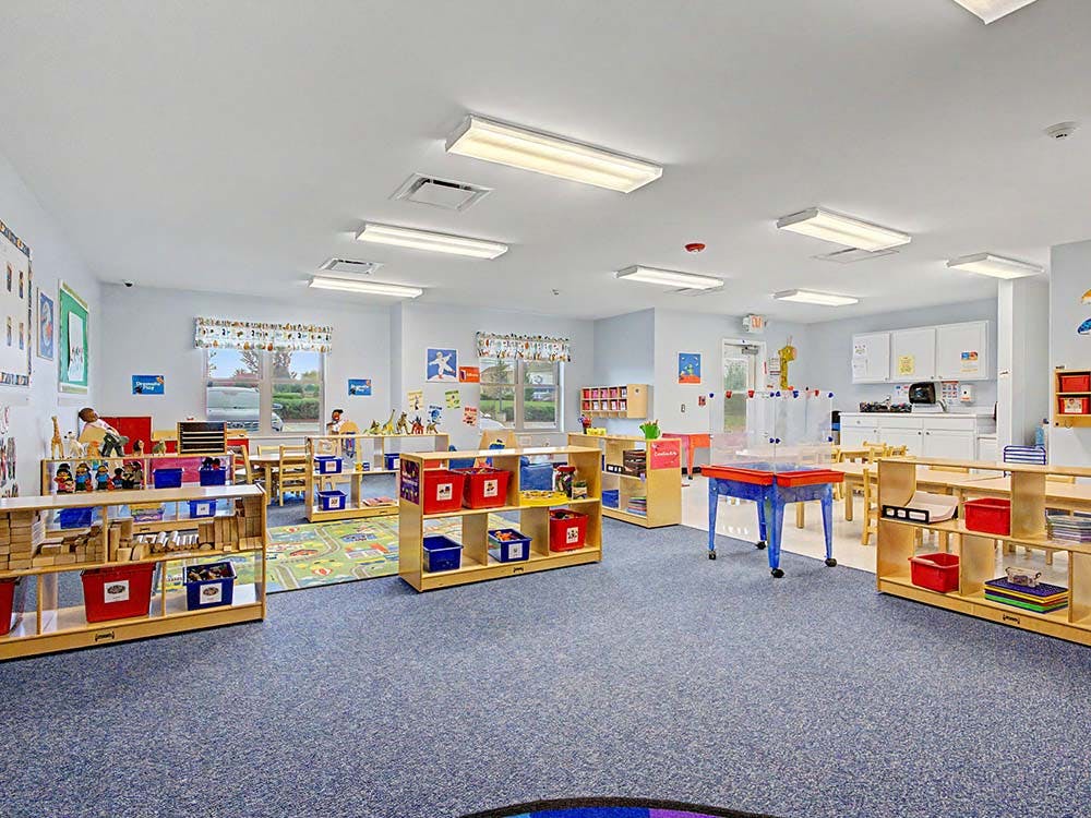 Bright, empty classroom with several low shelves and small tables
