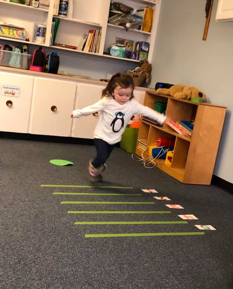 Child jumping over green lines on the floor