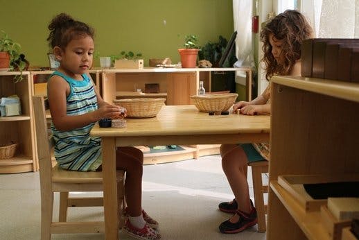 Two children sitting at a table in a classroom
