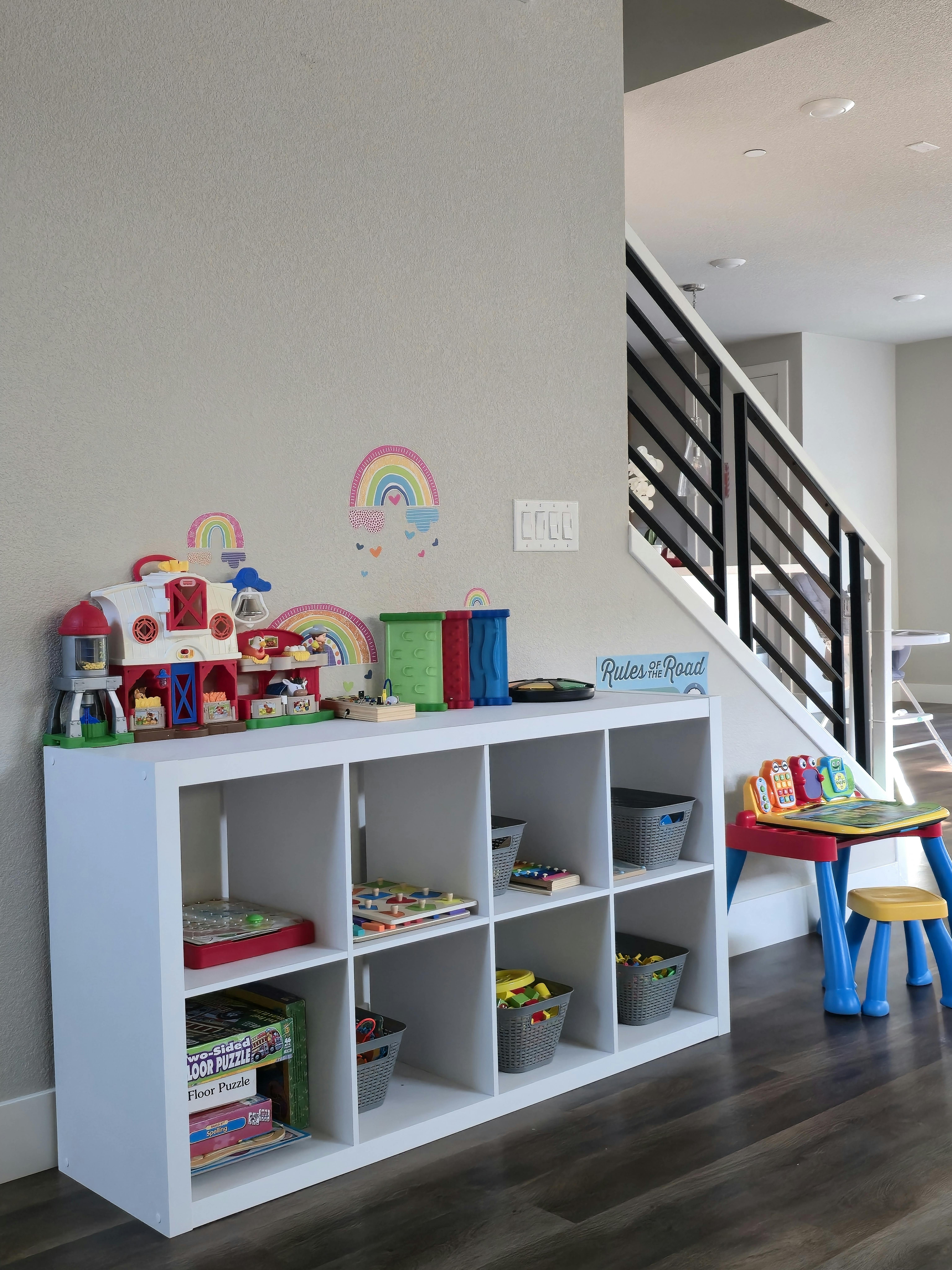 White cubby shelf with toys and a small child's table and chair