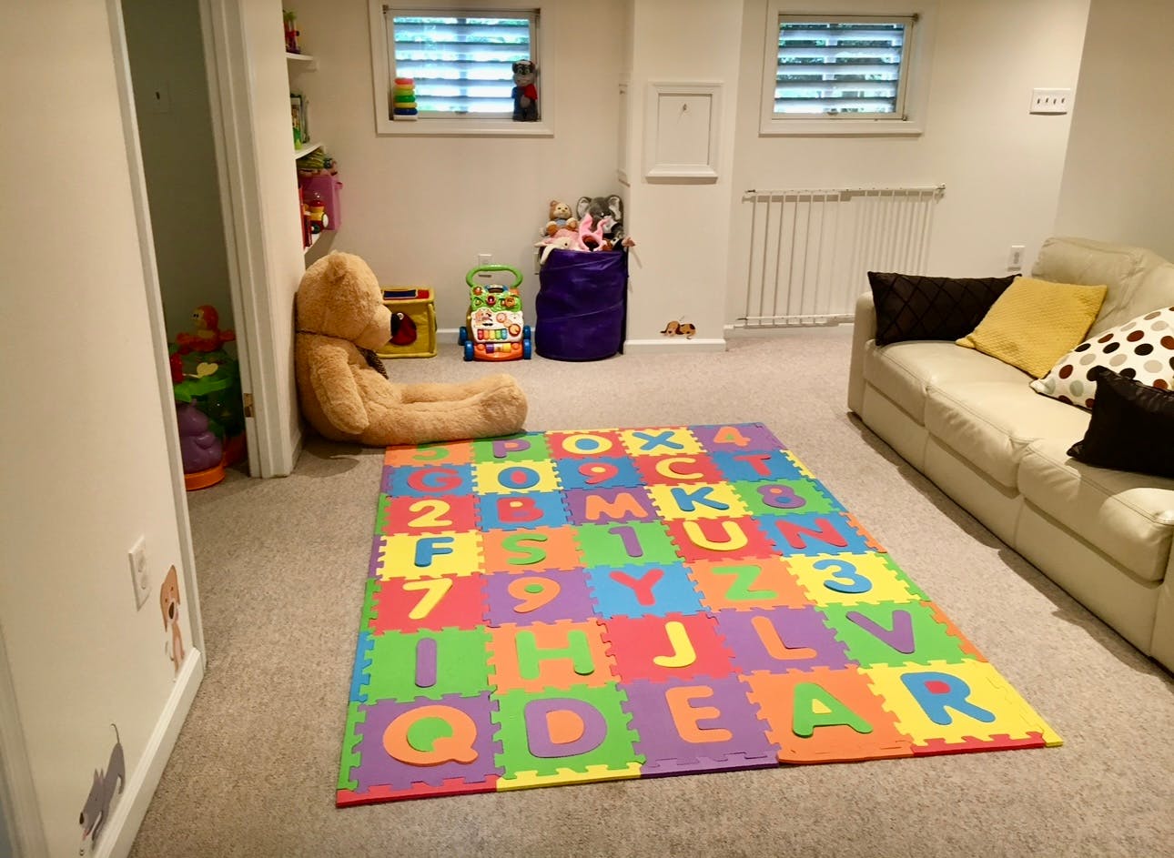 Playroom with alphabet mat, teddy bear, and sofa