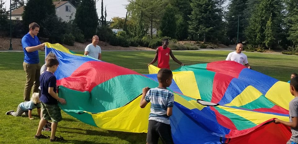 People and children holding a colorful parachute on grass