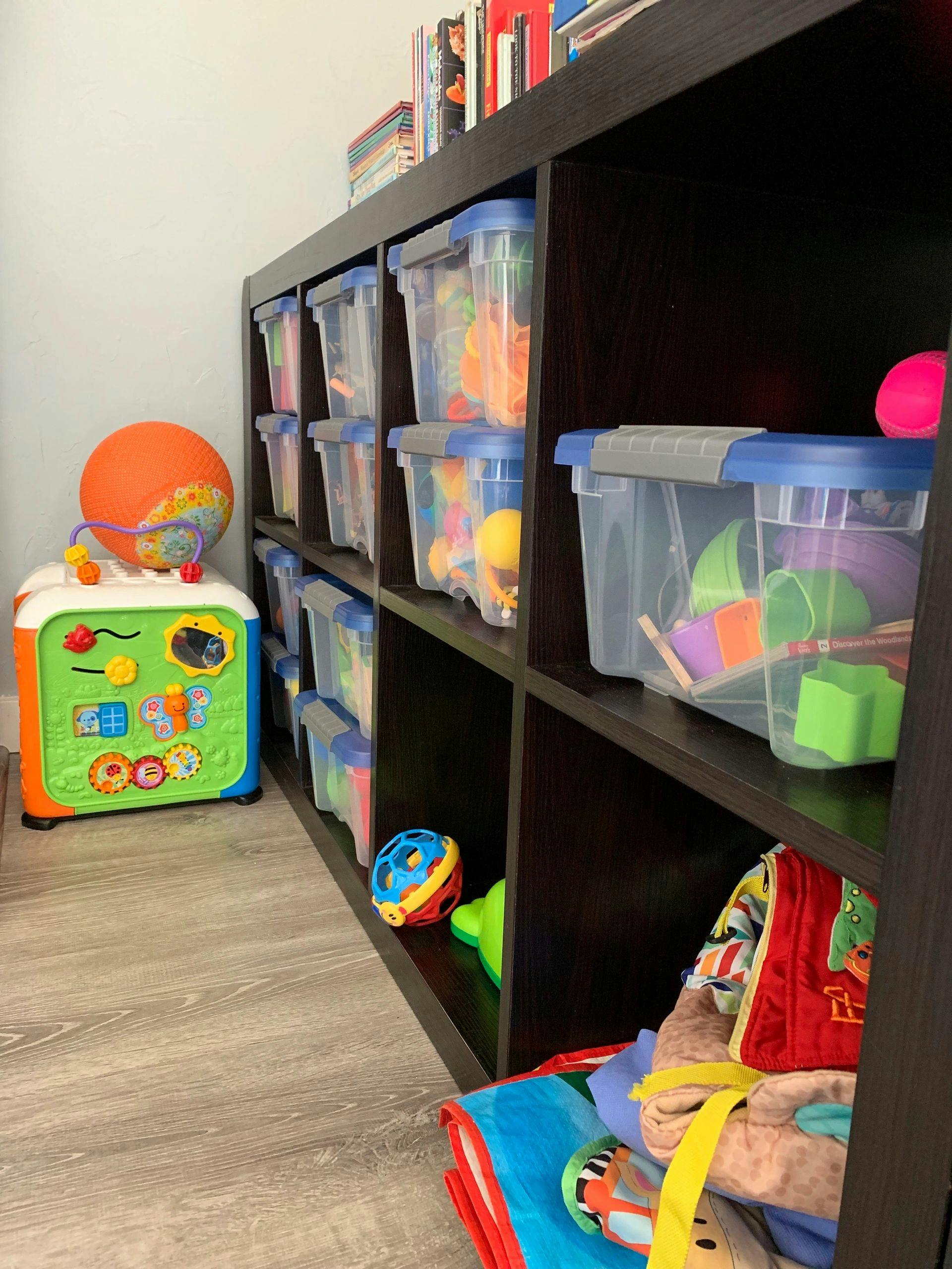 Toy storage shelves with clear bins of toys and an activity cube