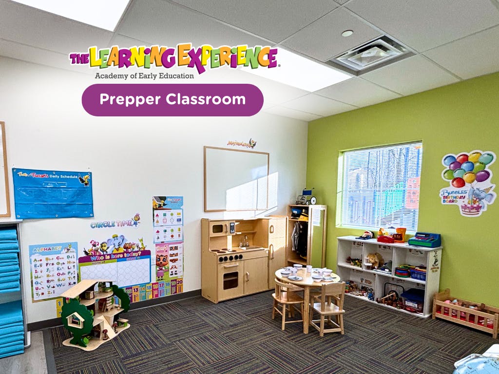 Classroom with play kitchen, small table and chairs, and learning posters