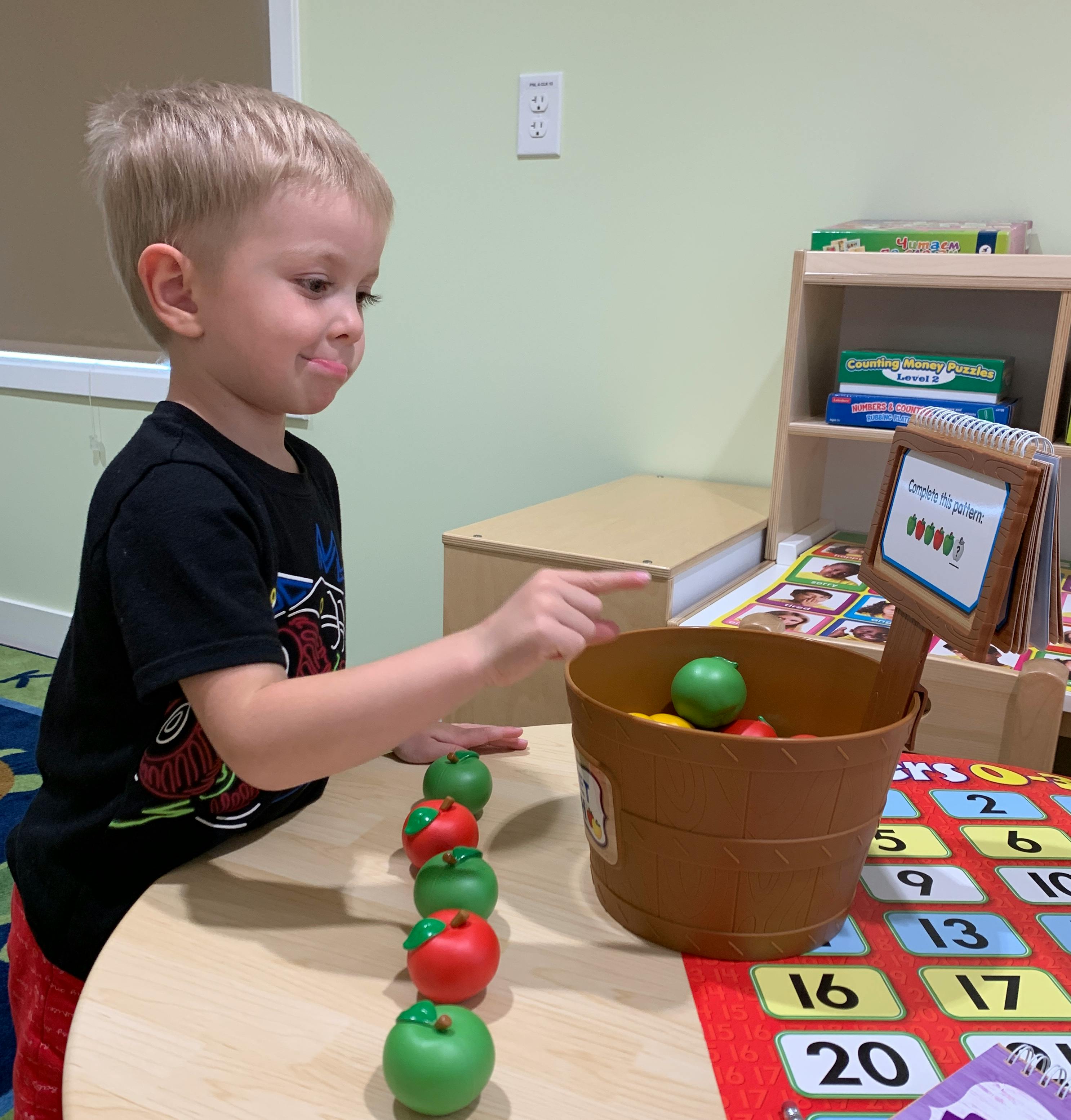 Child playing with toy apples and a bucket