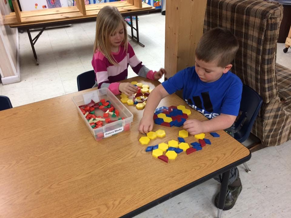 Two children playing with colorful geometric shapes at a table